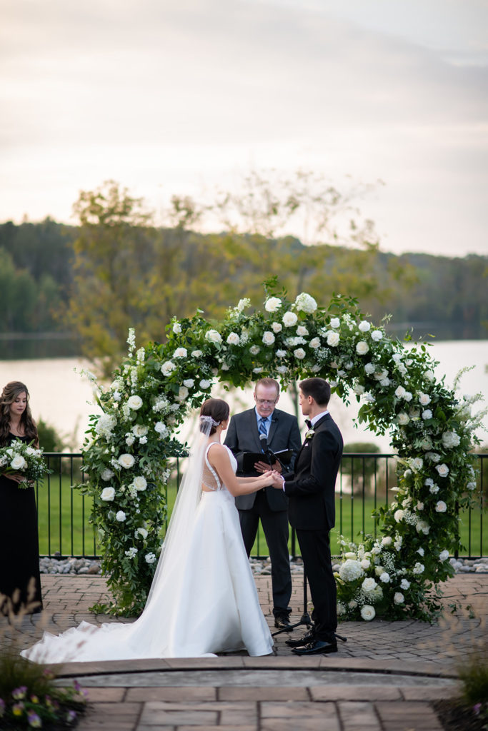 classy and elegant wedding ceremony with circle arch and lake view