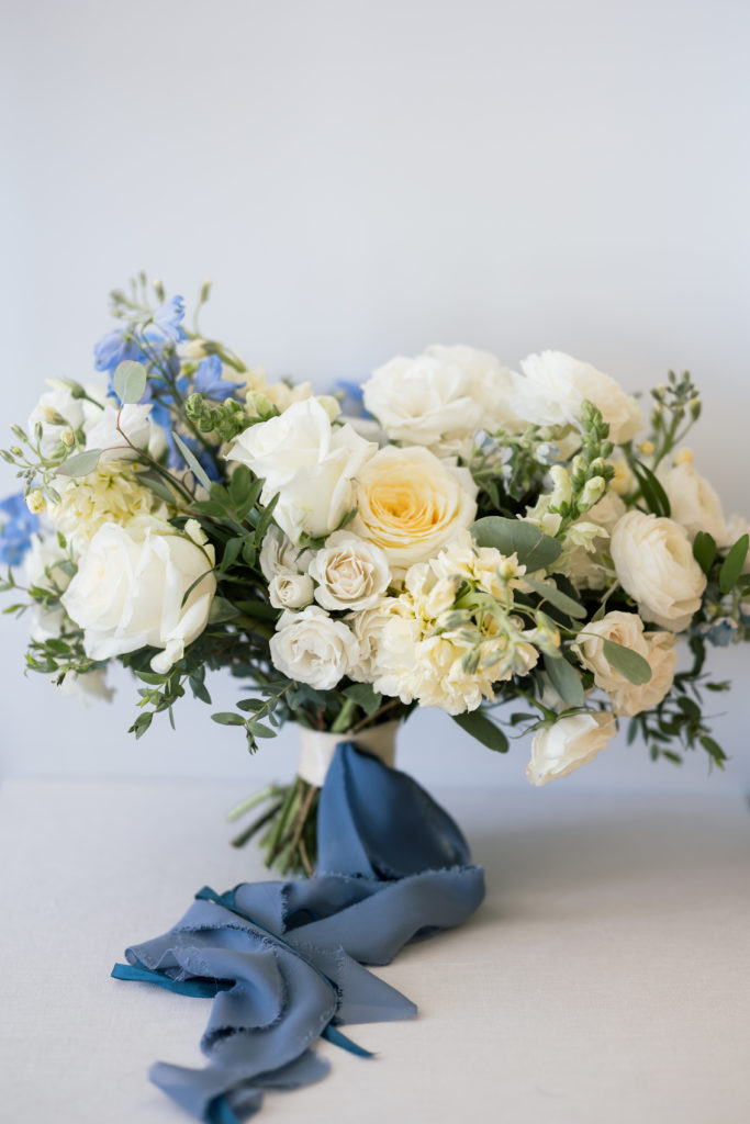 A classy white and green bridal bouquet with touches of blue and draping silk ribbon