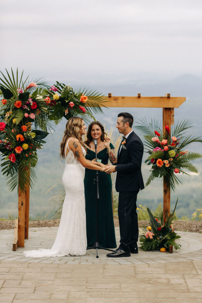 Bride and groom wedding ceremony under tropical floral arch