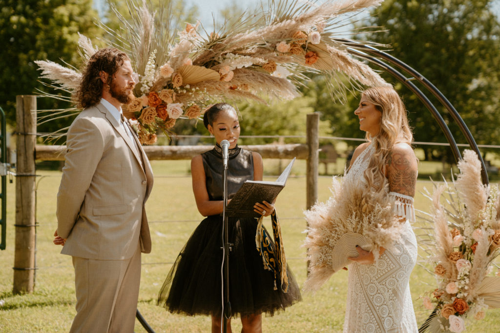boho meets western wedding ceremony featuring a dried and floral circle arch
