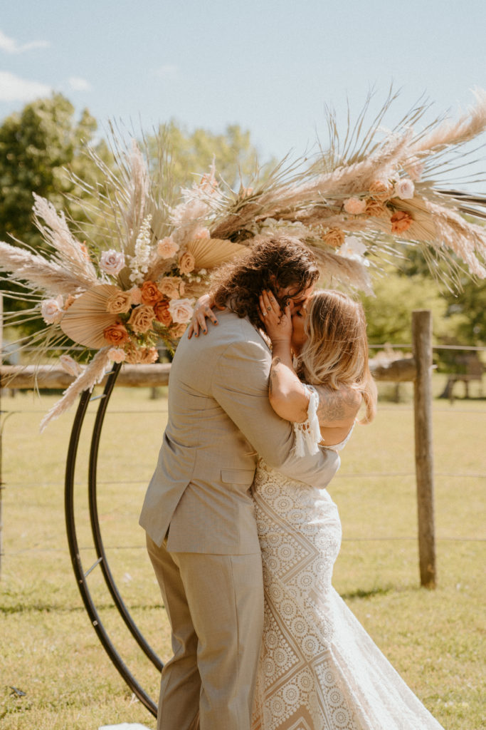 Boho Wedding First kiss featuring circle arch and pampas grass
