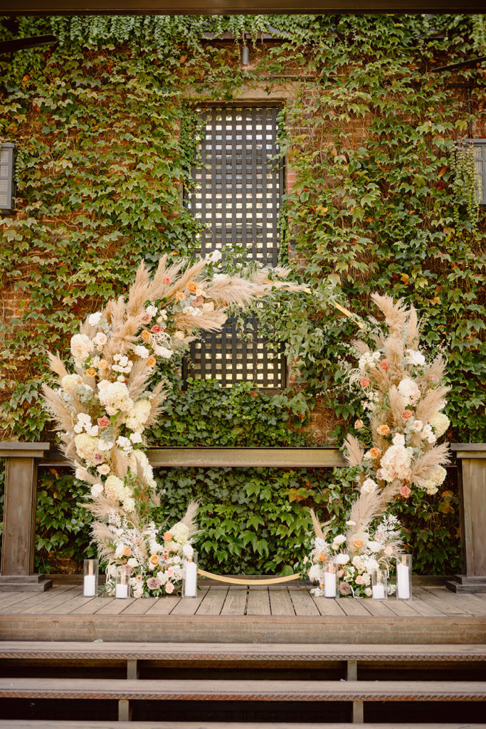 industrial meets boho wedding ceremony arch with pampas grass hydrangea and roses