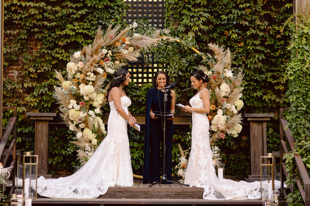 industrial meets boho wedding ceremony with a circle arch covered in pampas grass, hydrangea and roses