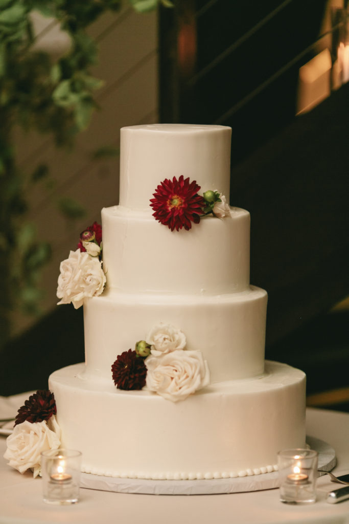 minimal wedding cake with burgundy and white floral accents