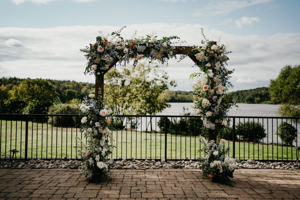 soft pastel wedding ceremony with floral arch filled with hydrangea and roses