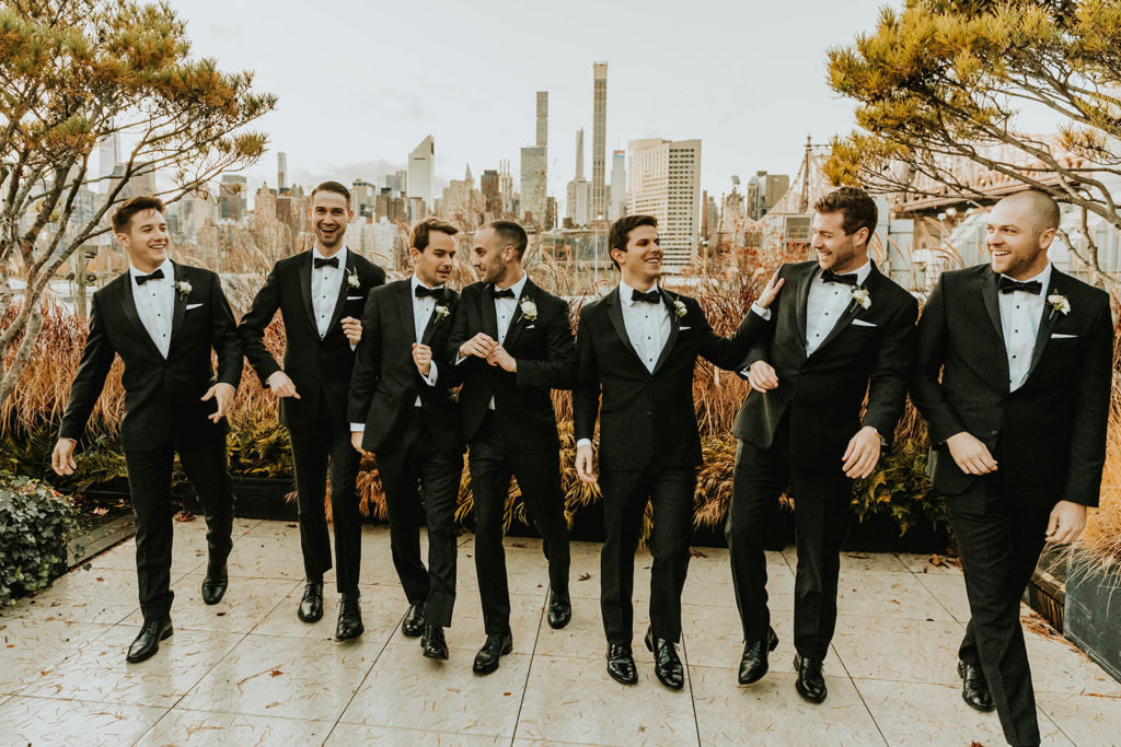 Groom and his groomsmen in all black suits with the city skyline
