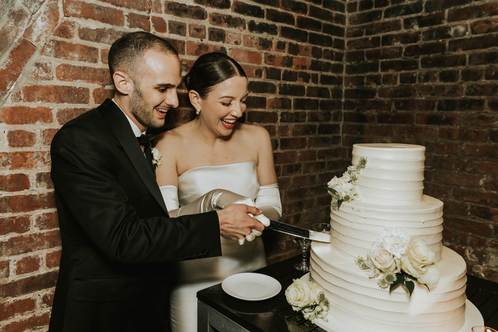 Bride and groom cutting their all white cake with a floral touch