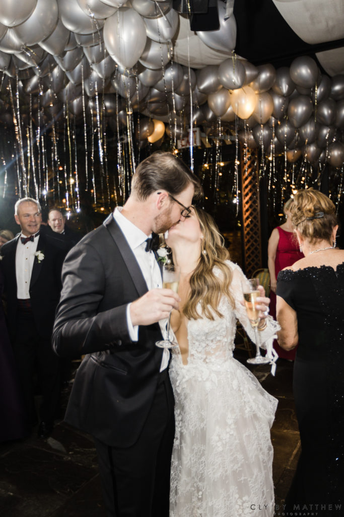 Bride and Groom Champagne Kiss Under Balloons Chic City Wedding